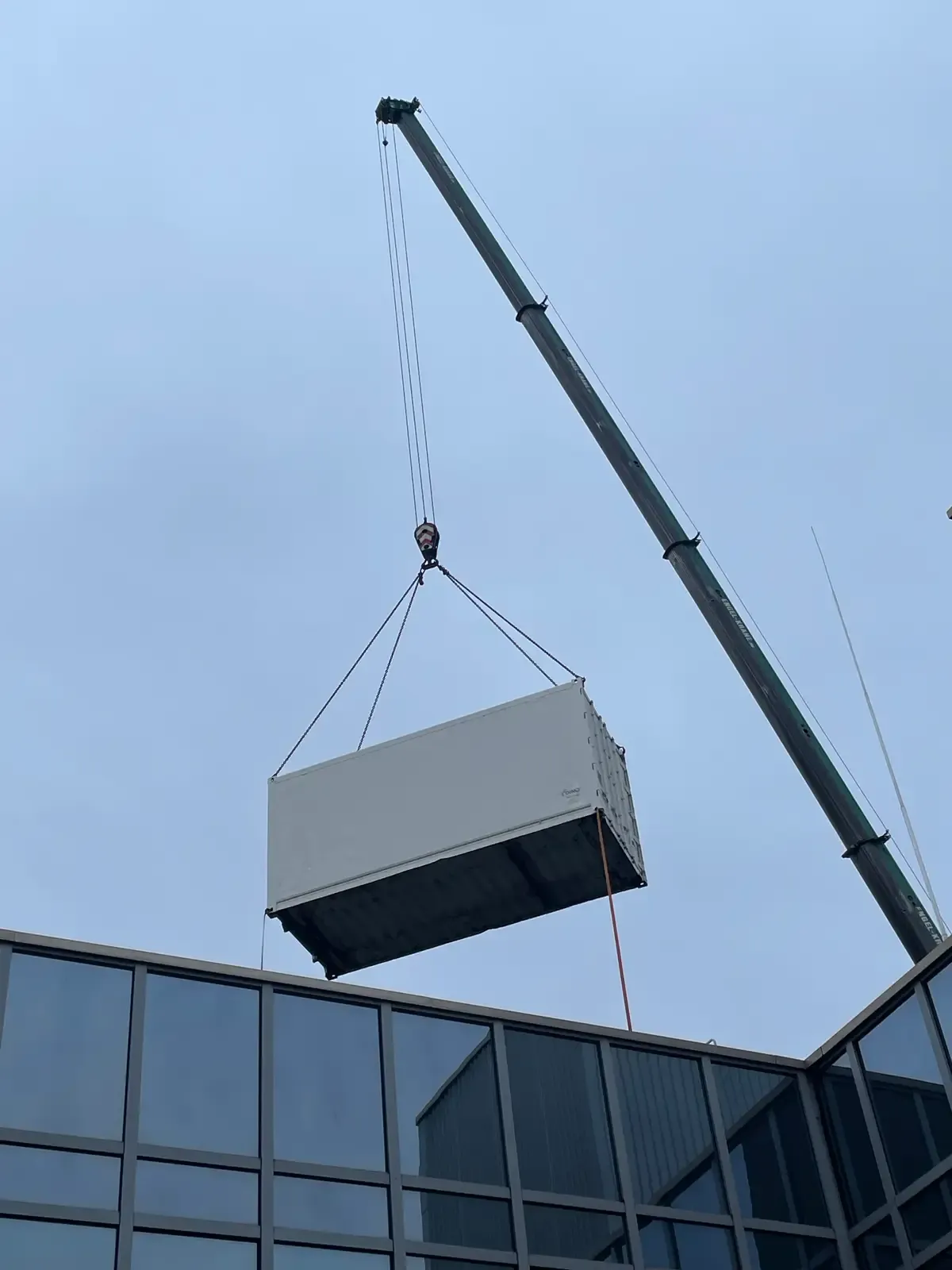 DINO container solution being lifted over a building by crane